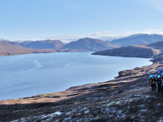 The rising sun tries to catch the hikers as they walk the southern hillside of the fjord.