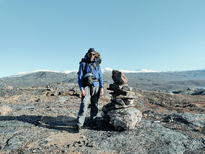 Kieran standing to the left of a typical ACT Cairn, the land stretches out forever behind him.